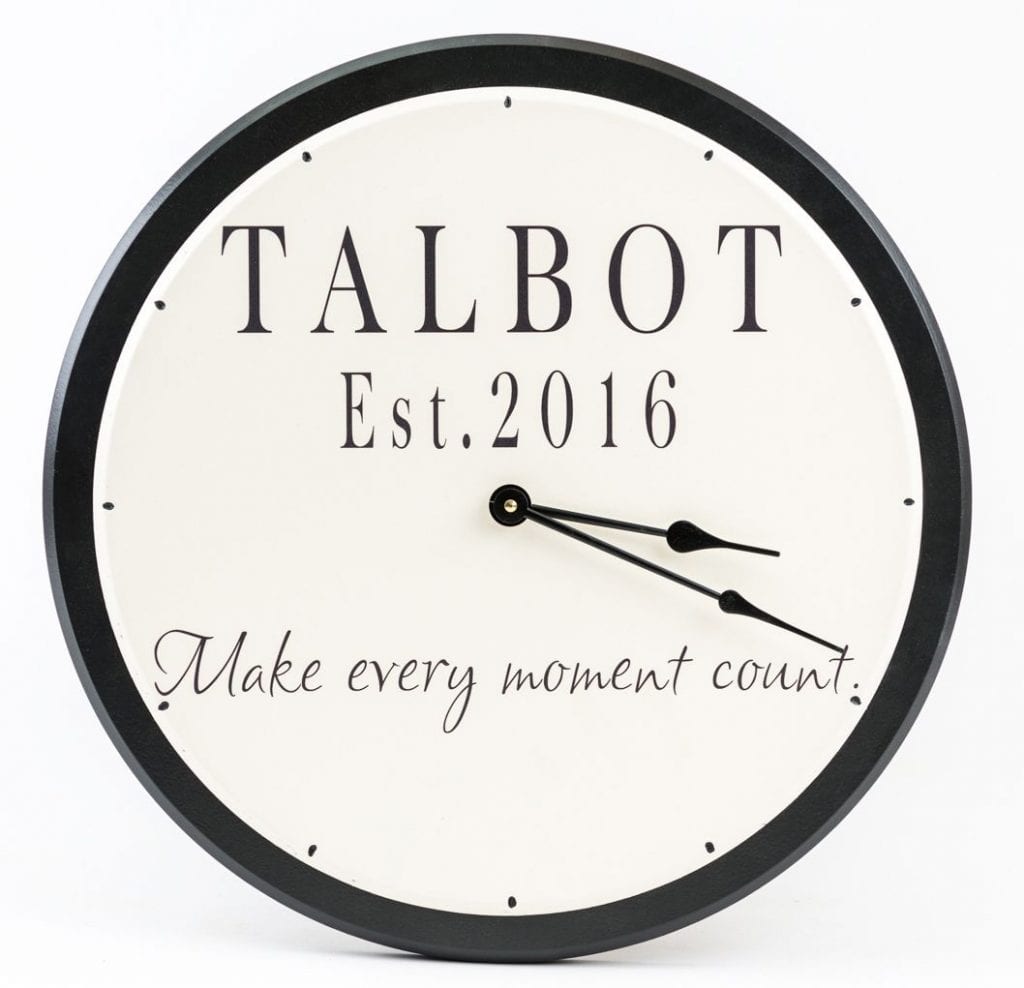 Large personalized wooden wall clock with family name and round black trim with white background.