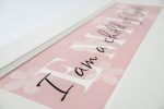 Girls room decoration personalized name sign. Pink wood sign with white flowers, white text, and white wood frame.