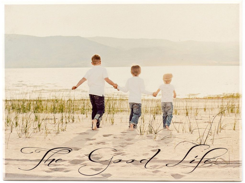 personalized wood picture of three children walking in sand next to a lake with the text, "the good life"