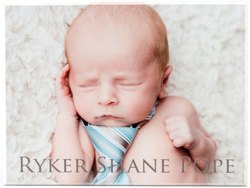 personalized wood picture of a baby with the text, "ryker shane pope" centered at bottom of image