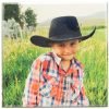 wood print photo of kid wearing a cowboy hat in a grass field